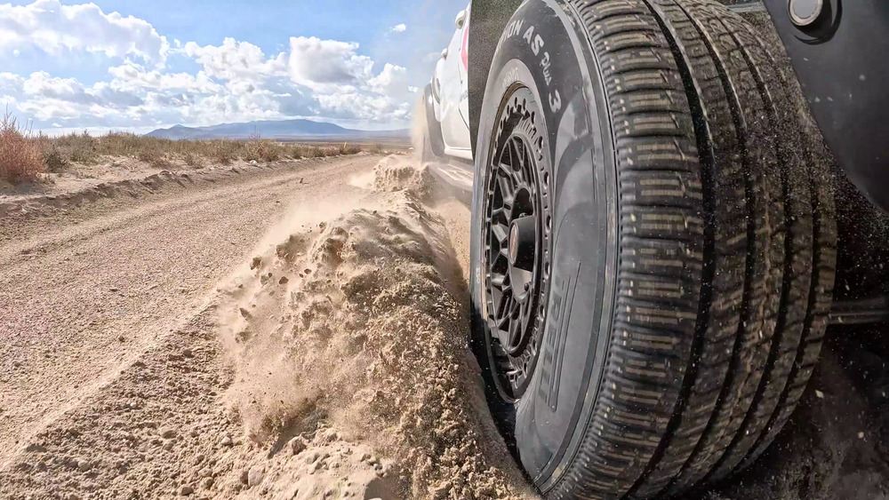 Pneumatico Pirelli Scorpion AS Plus 3 che solleva sabbia smossa accanto a un Ford Ranger Raptor